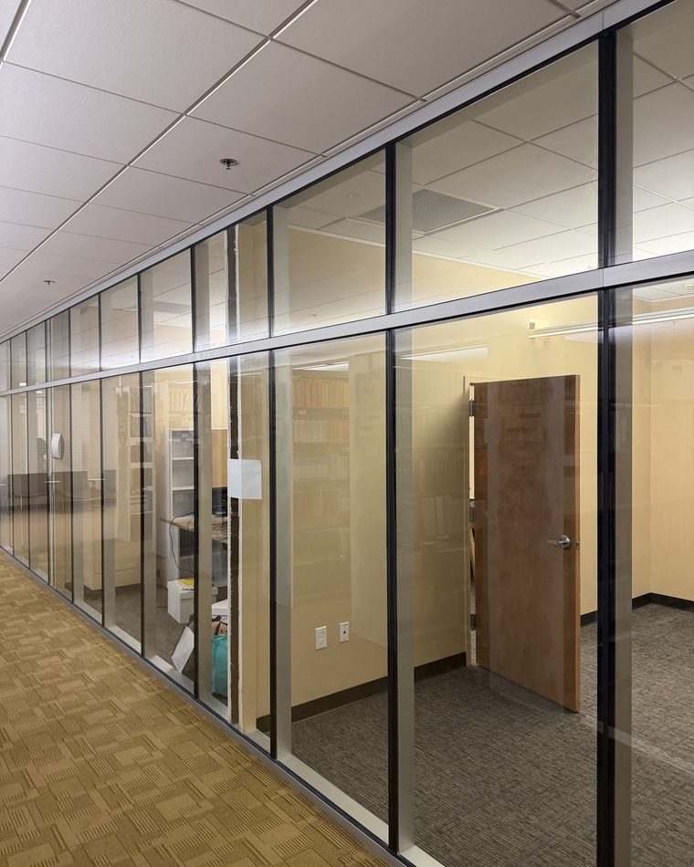 Before: clear glass office partitions along a corridor in the Atlanta University library, with desks and shelving visible behind them