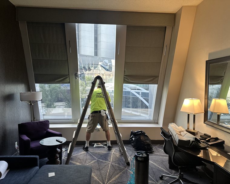 Premier Glass Coatings installer applying security film to a guest room window at an Atlanta hotel